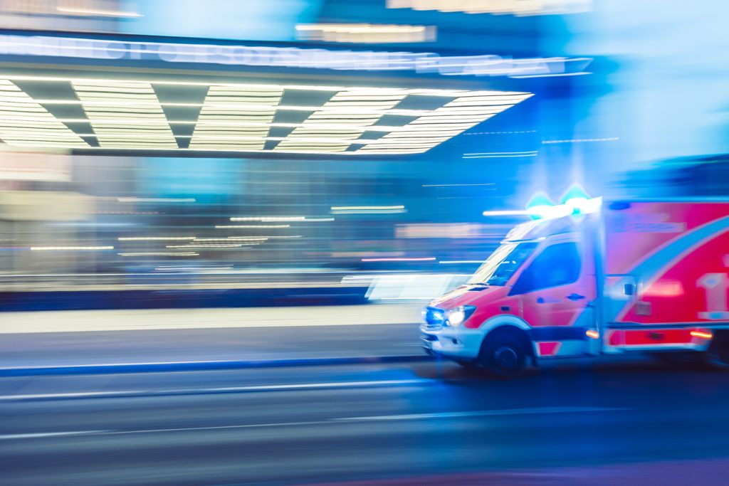 Photo of an ambulance with lights on in motion.