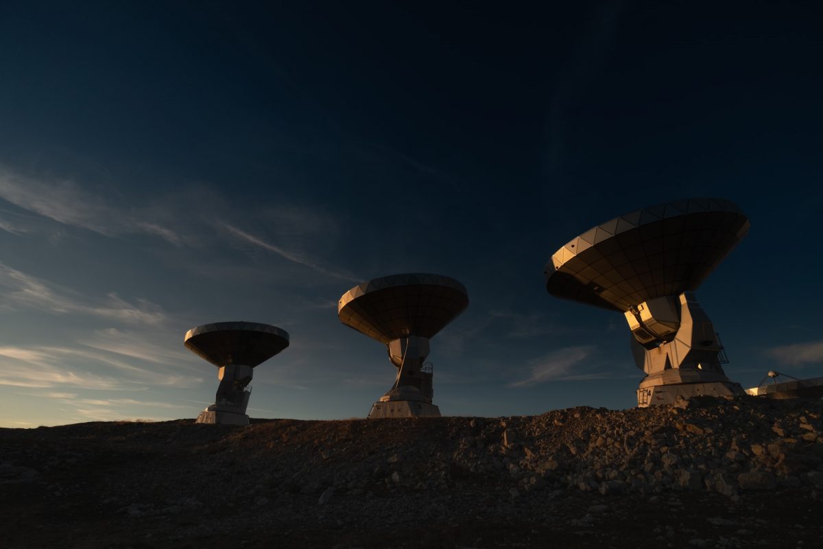 Three radio telescopes pointed to the sky on a rocky ridge