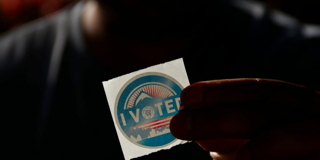 A silhouette holding an "I Voted" sticker