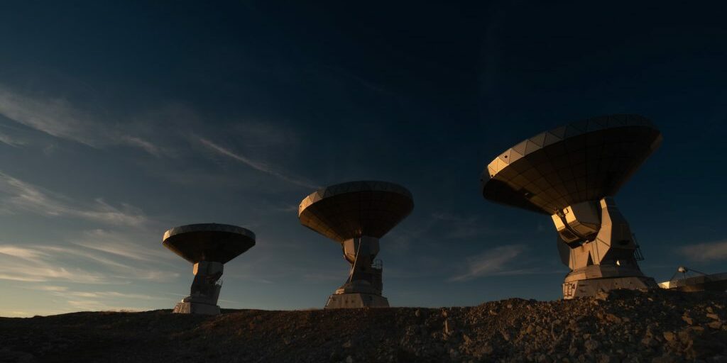 Three radio telescopes pointed to the sky on a rocky ridge